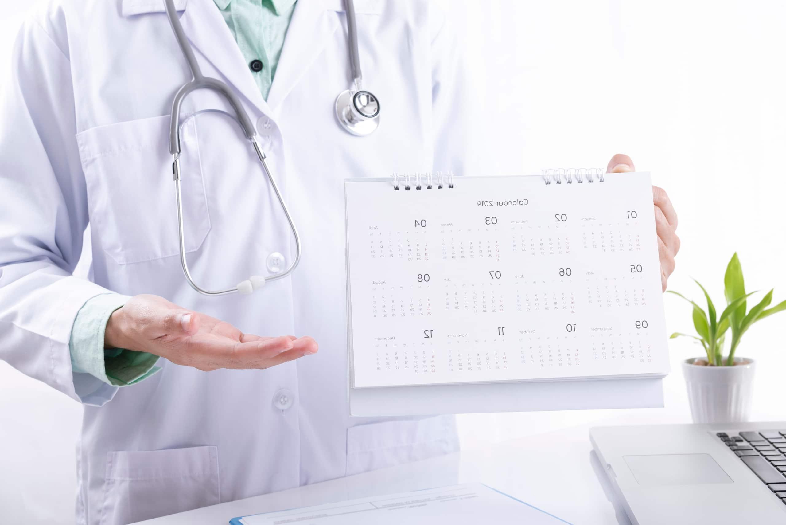 Close up of a medical professional holding a desk calendar